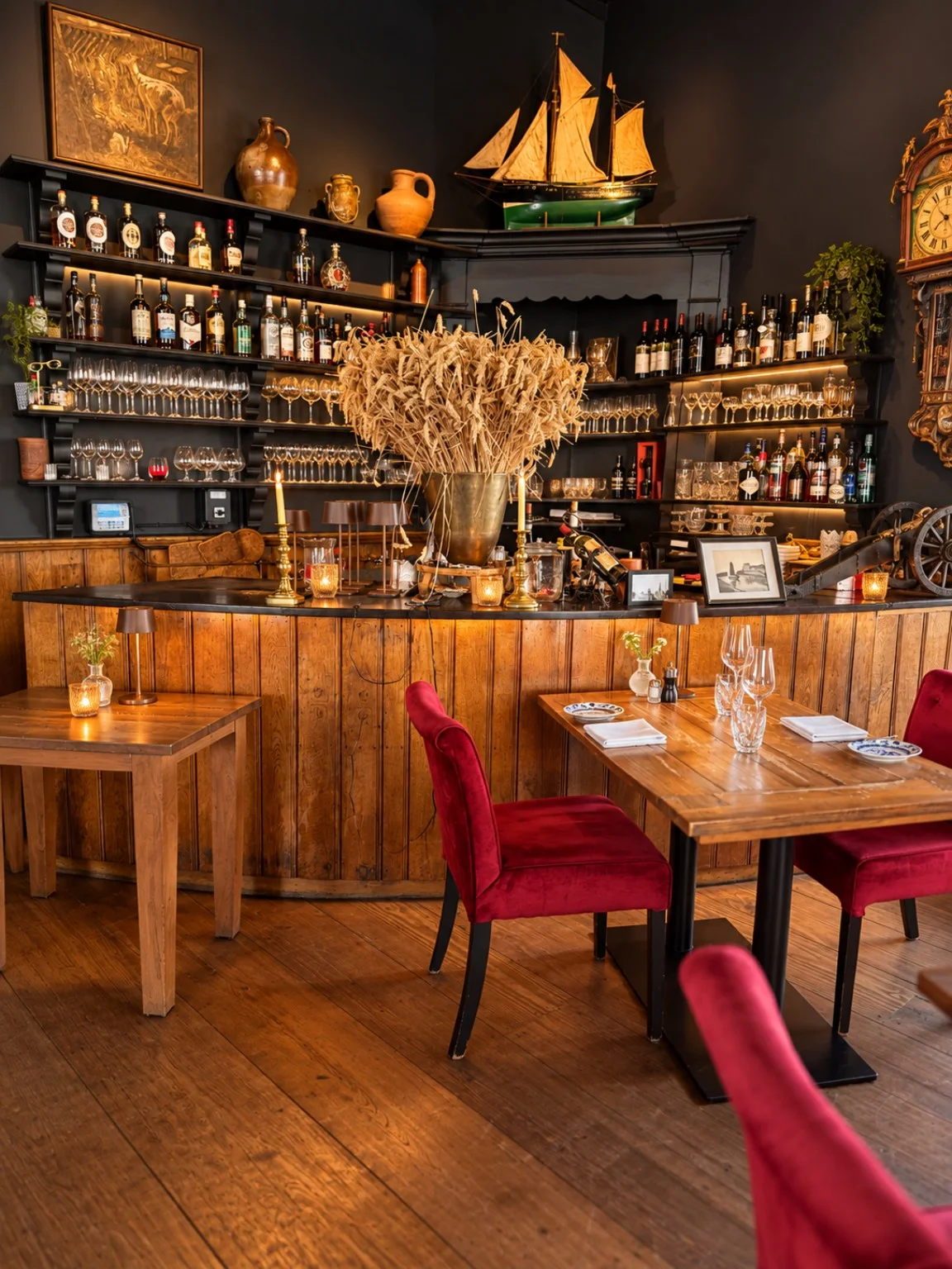 De houten bar met scheepsmodel, gedekte tafels en rode stoelen