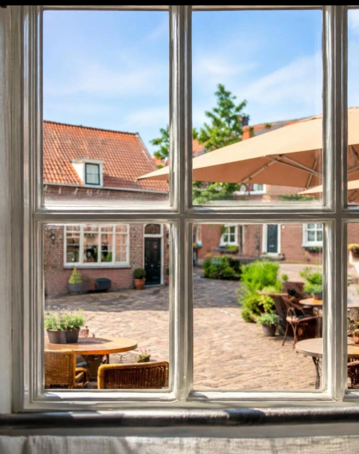 Uitzicht door het raam van de Herbergierskamer op het terras en de huizen van Veere